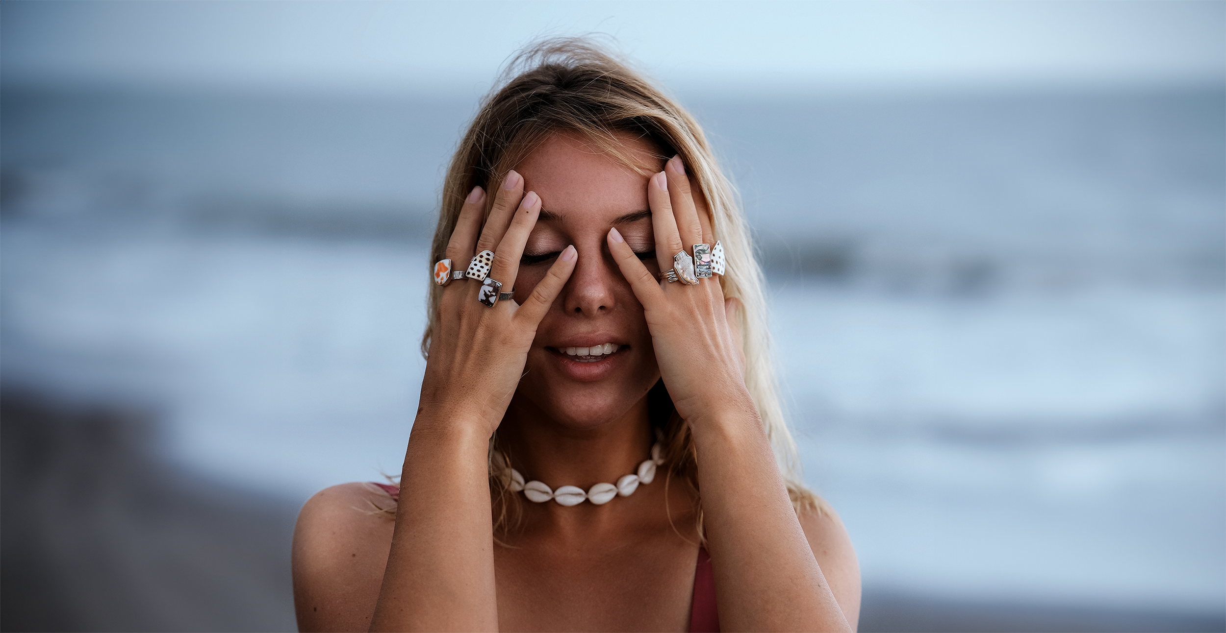 woman wearing multiple 925 sterling silver shell rings with natural shell inlays, styled in a coastal, beach-inspired look. Perfect ocean-inspired jewelry for bohemian and beachwear fashion enthusiasts