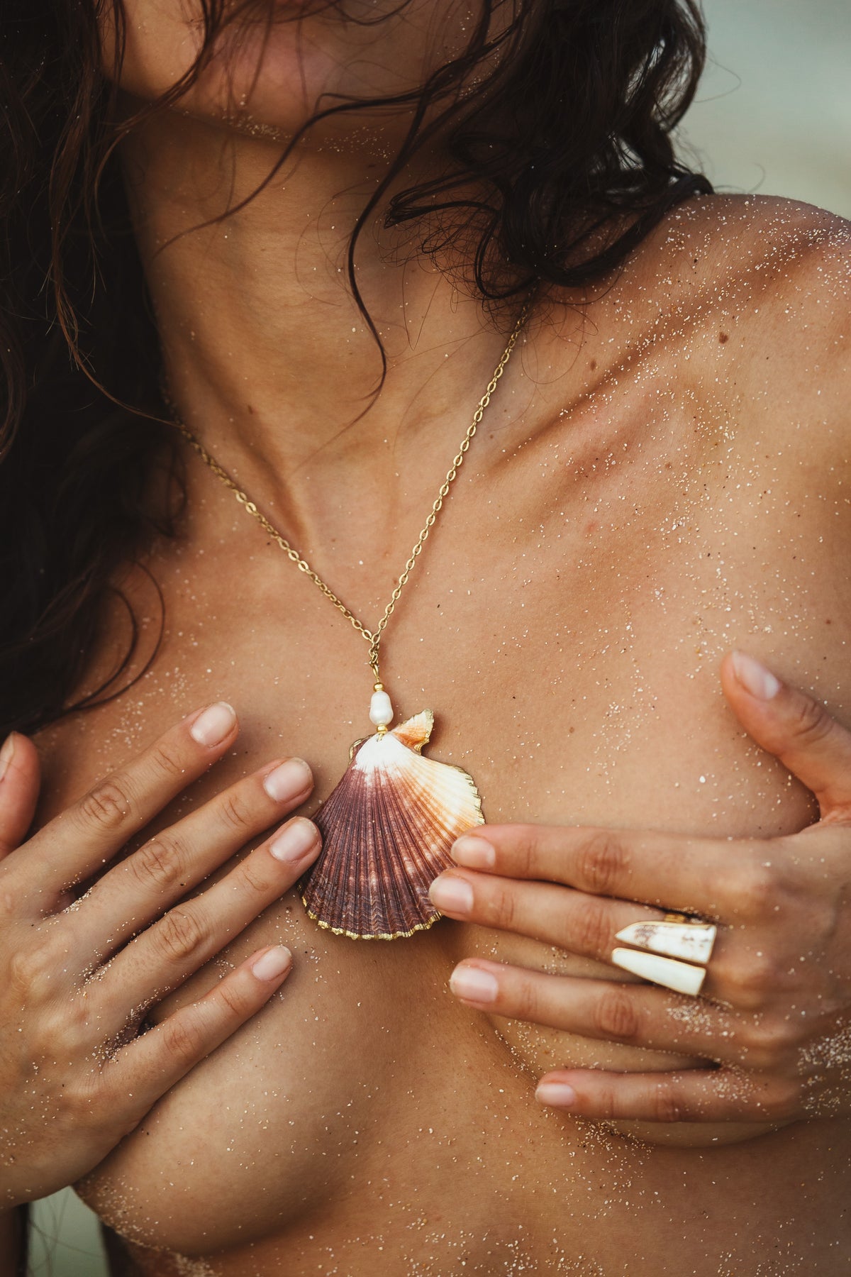 a woman wearing a gold seashell necklace with a pearl pendant, embodying bohemian beach style. Ocean-inspired jewelry crafted with natural shell and pearl, ideal for coastal fashion and sea lovers seeking elegant, nature-inspired accessories